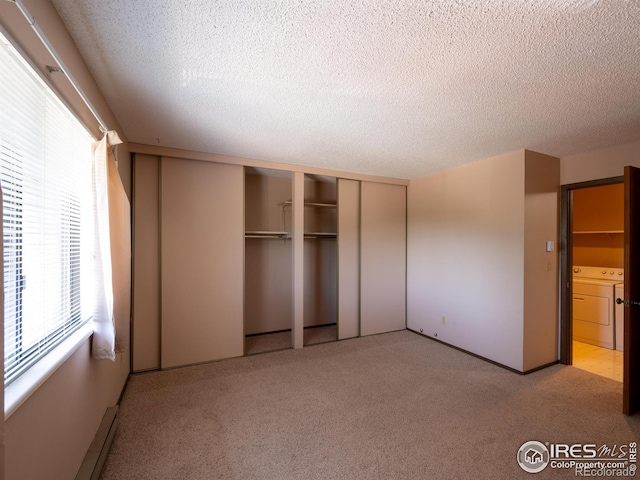 unfurnished bedroom with carpet floors, a closet, a textured ceiling, and separate washer and dryer