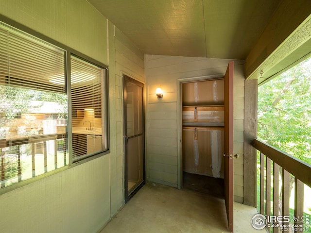 hallway featuring lofted ceiling, unfinished concrete floors, and a wealth of natural light