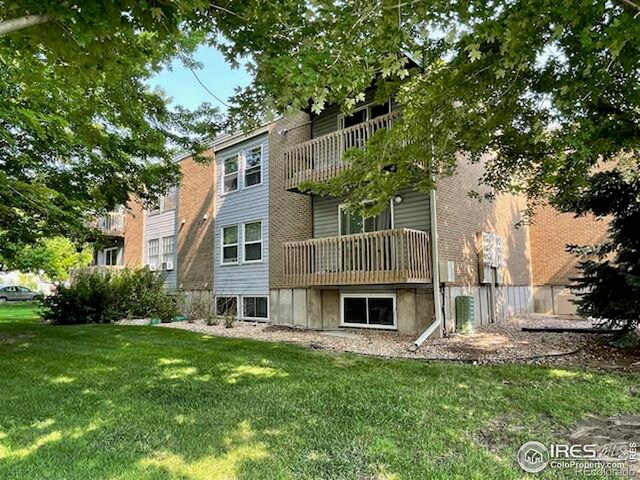 rear view of property featuring a balcony and a lawn