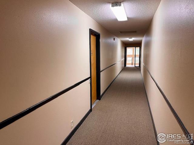 hall with a textured ceiling and carpet