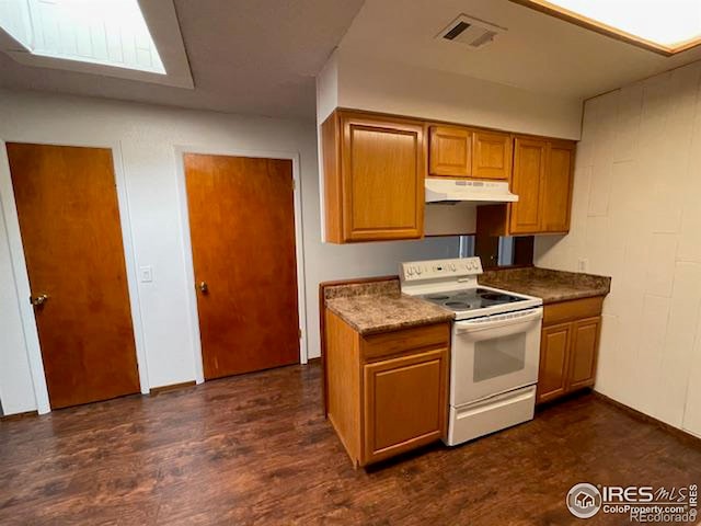 kitchen featuring visible vents, dark wood finished floors, brown cabinets, under cabinet range hood, and white range with electric cooktop