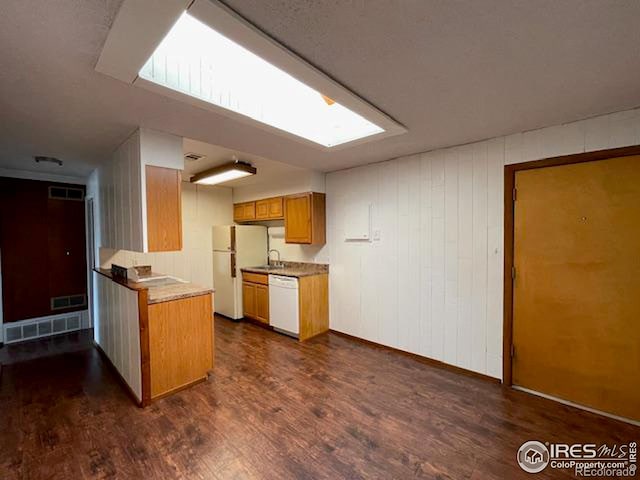 kitchen with white appliances, dark wood-style flooring, a skylight, visible vents, and light countertops