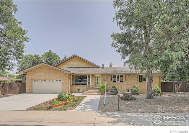 single story home with a garage, brick siding, concrete driveway, and fence