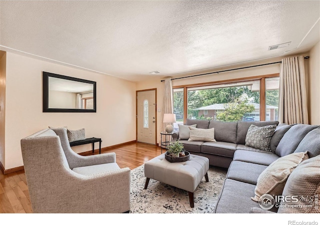 living room with a textured ceiling and light hardwood / wood-style floors