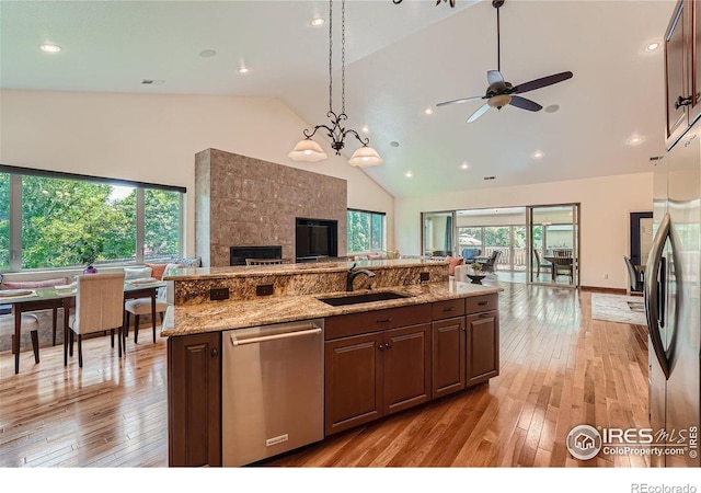 kitchen with high vaulted ceiling, light wood-style flooring, a sink, open floor plan, and stainless steel appliances