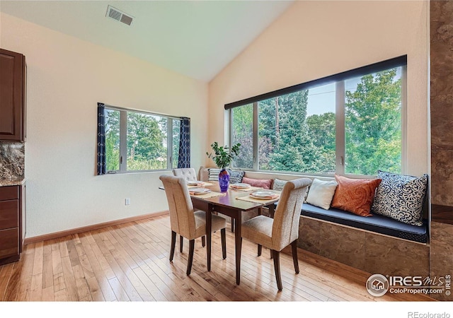 dining space with visible vents, baseboards, high vaulted ceiling, and light wood finished floors