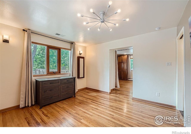 spare room with an inviting chandelier and light hardwood / wood-style flooring