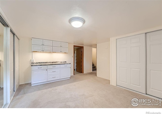 kitchen featuring light colored carpet and white cabinets