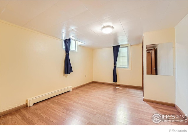 unfurnished room featuring a baseboard heating unit, baseboards, and wood finished floors