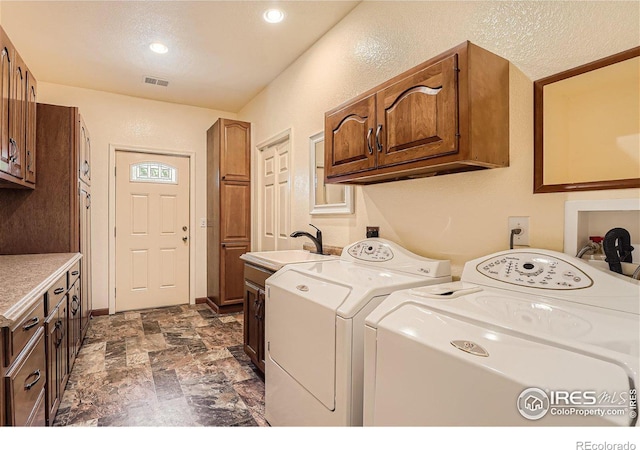 laundry room featuring visible vents, washing machine and dryer, cabinet space, a textured ceiling, and a sink