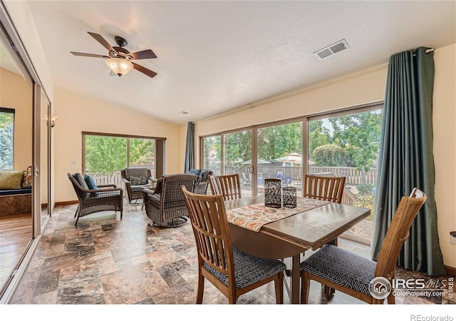 dining room featuring vaulted ceiling, ceiling fan, and a textured ceiling