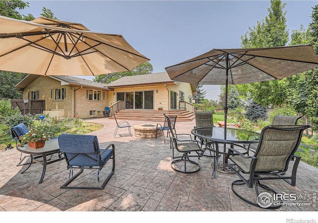 view of patio with outdoor dining area, entry steps, and an outdoor fire pit