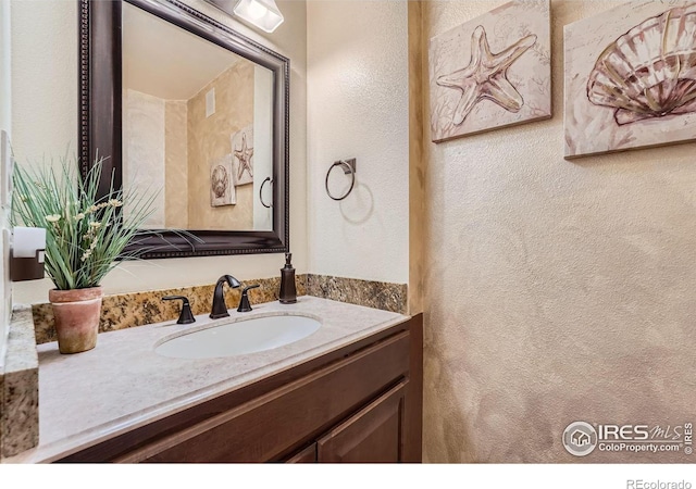 bathroom featuring vanity and a textured wall