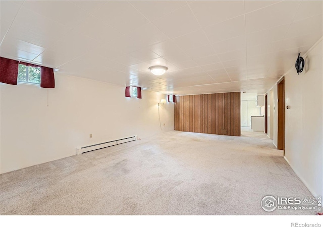 interior space with carpet flooring, wood walls, and a baseboard heating unit