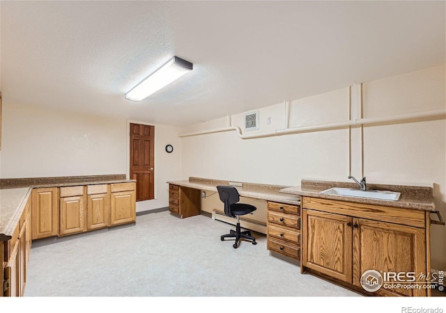 home office with a textured ceiling, visible vents, baseboard heating, and a sink