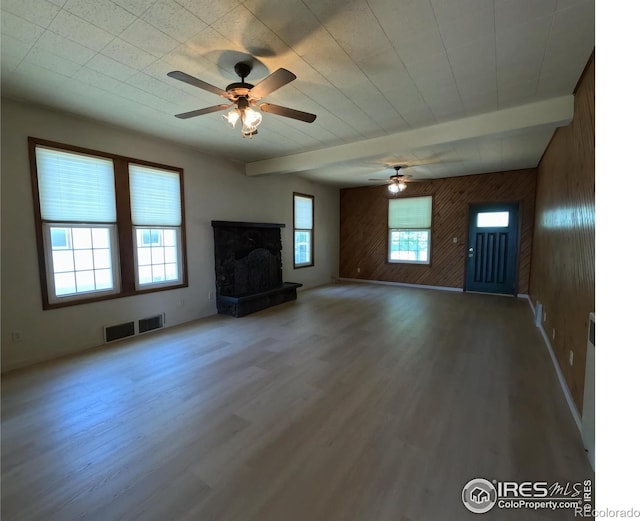 619 Curtis St, Brush, CO 80723 - unfurnished living room with ceiling fan, wood walls, beam ceiling, wood finished floors, and a fireplace with raised hearth