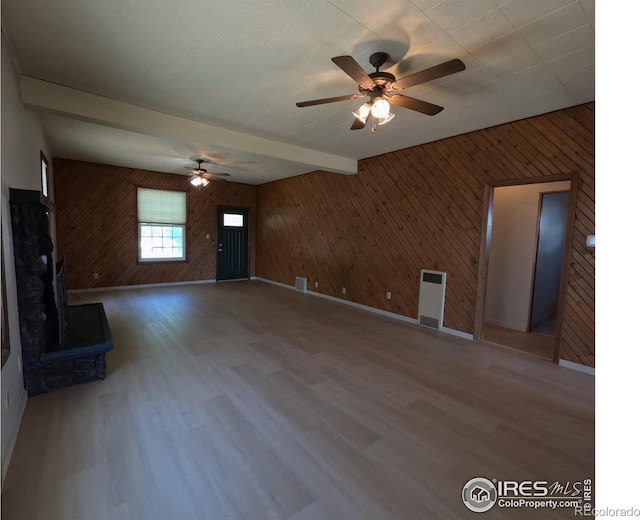 619 Curtis St, Brush, CO 80723 - unfurnished living room with wood walls, wood finished floors, ceiling fan, and beam ceiling