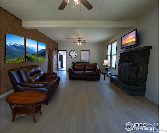 619 Curtis St, Brush, CO 80723 - living room with ceiling fan, beamed ceiling, wood finished floors, wooden walls, and a fireplace with raised hearth