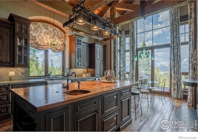 kitchen with hardwood / wood-style floors, decorative backsplash, wooden counters, and a sink