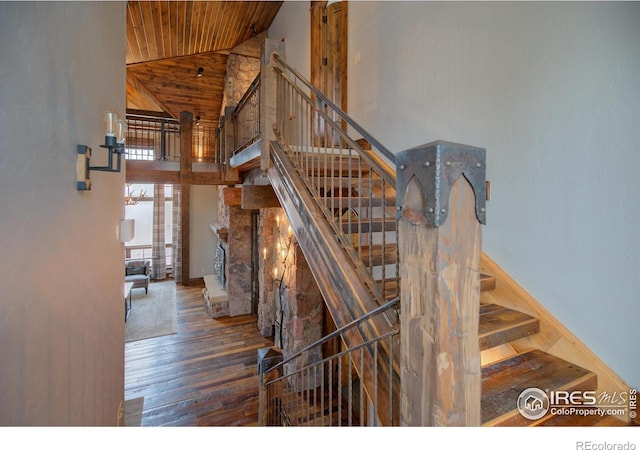 stairs featuring high vaulted ceiling, a fireplace, wooden ceiling, and wood finished floors