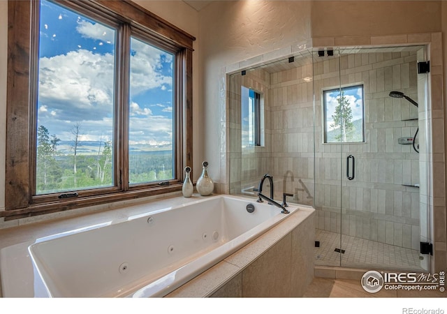 full bathroom with a textured wall, a jetted tub, and a shower stall