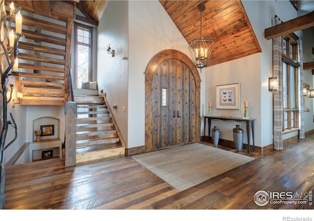 entryway with high vaulted ceiling, wooden ceiling, hardwood / wood-style flooring, stairway, and an inviting chandelier