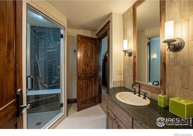 full bathroom with tasteful backsplash, a stall shower, vanity, and tile walls