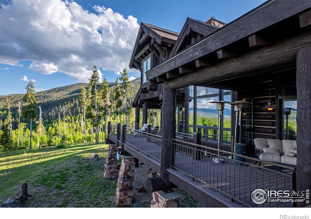 view of property exterior featuring a lawn, a mountain view, and a view of trees