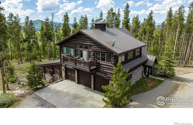 view of front facade featuring a standing seam roof, metal roof, a garage, stone siding, and driveway