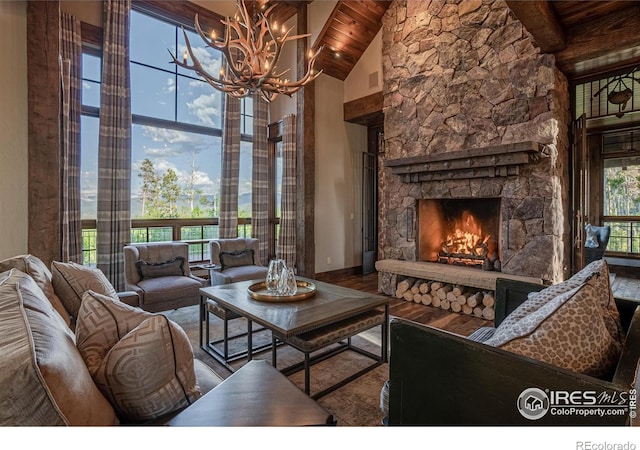 living room featuring high vaulted ceiling, a stone fireplace, wooden ceiling, wood finished floors, and beamed ceiling