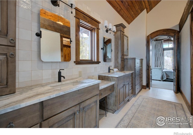 bathroom featuring lofted ceiling, a wealth of natural light, backsplash, and a sink