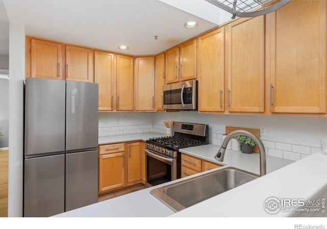 kitchen with appliances with stainless steel finishes, light countertops, a sink, and recessed lighting