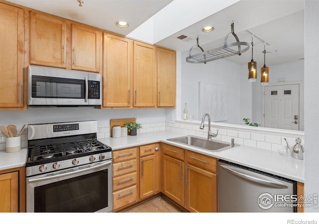 kitchen featuring sink, light hardwood / wood-style floors, hanging light fixtures, and appliances with stainless steel finishes