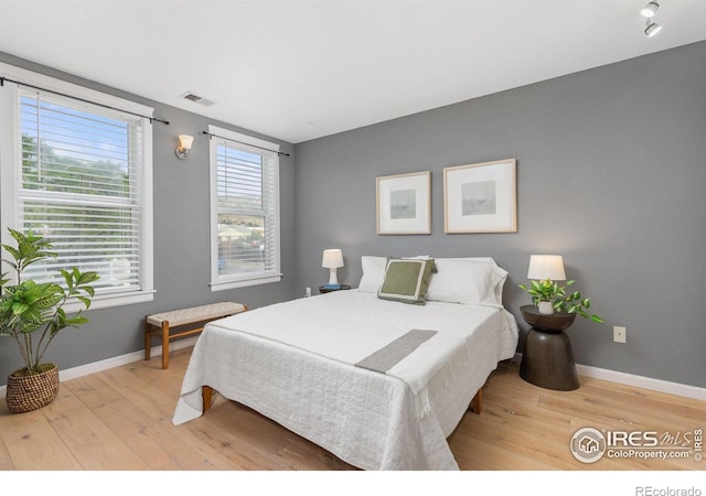 bedroom with wood finished floors, visible vents, and baseboards