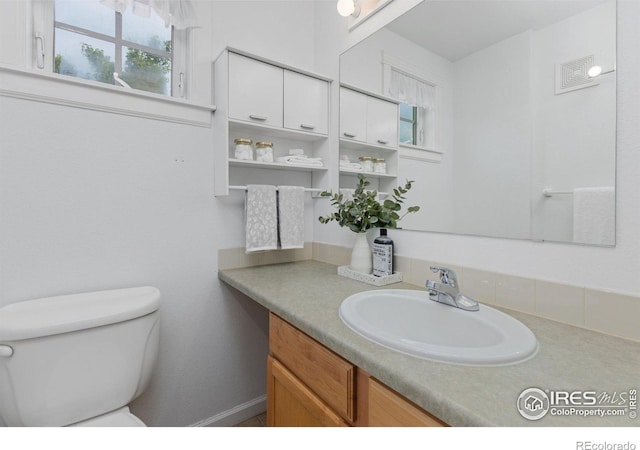 bathroom with visible vents, vanity, and toilet