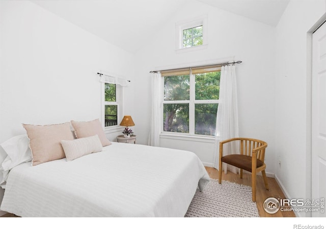 bedroom with high vaulted ceiling and light wood-type flooring