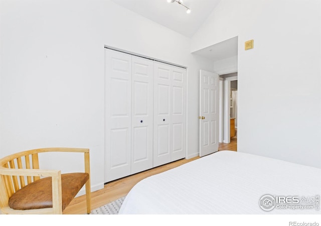 bedroom with lofted ceiling, a closet, and light wood-style flooring