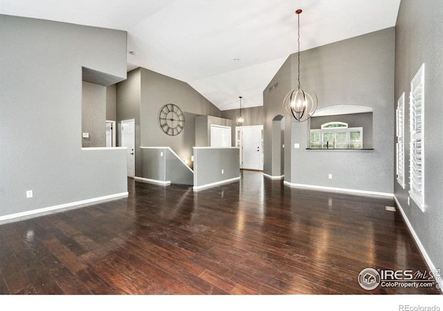 unfurnished living room featuring hardwood / wood-style flooring, high vaulted ceiling, and a chandelier