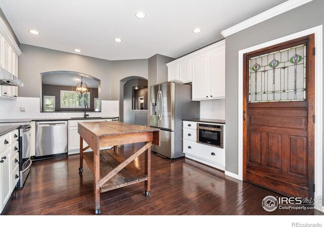 kitchen with stainless steel appliances, white cabinets, backsplash, dark hardwood / wood-style floors, and a notable chandelier