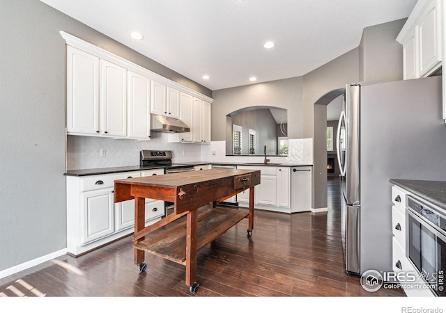 kitchen with decorative backsplash, dark hardwood / wood-style flooring, appliances with stainless steel finishes, and white cabinets