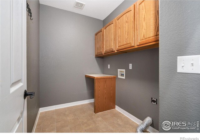 washroom with light tile patterned flooring, washer hookup, hookup for an electric dryer, and cabinets