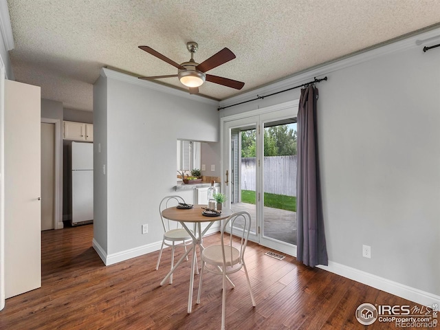 unfurnished dining area featuring dark wood-type flooring, ornamental molding, and a textured ceiling