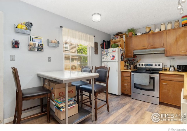 3300 Madison Ave, Boulder, CO 80303 - kitchen featuring freestanding refrigerator, a textured ceiling, under cabinet range hood, light wood-style floors, and stainless steel electric range oven