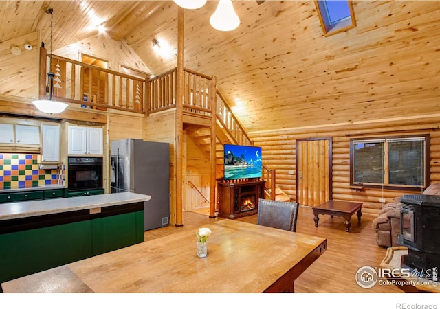 dining area featuring wood ceiling, high vaulted ceiling, log walls, a wood stove, and light wood-type flooring