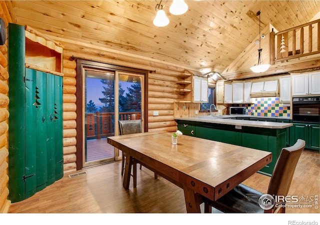 dining room featuring wooden ceiling, rustic walls, light wood-type flooring, and sink