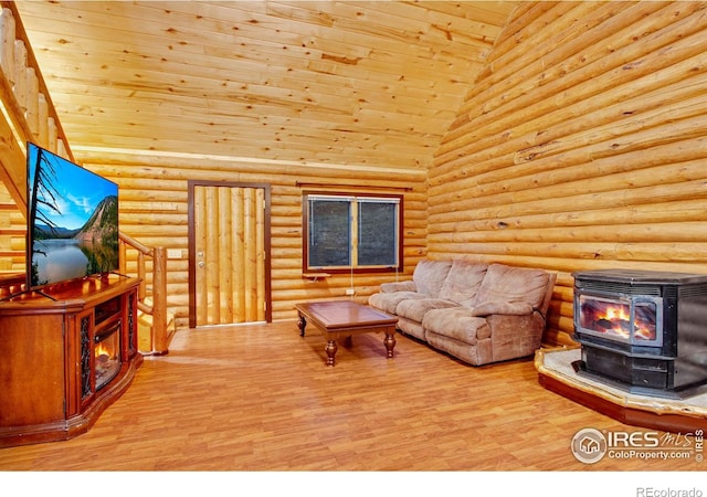 living room with wood ceiling, high vaulted ceiling, light hardwood / wood-style floors, a wood stove, and rustic walls