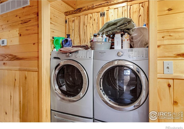 laundry area featuring wood walls and washer and dryer