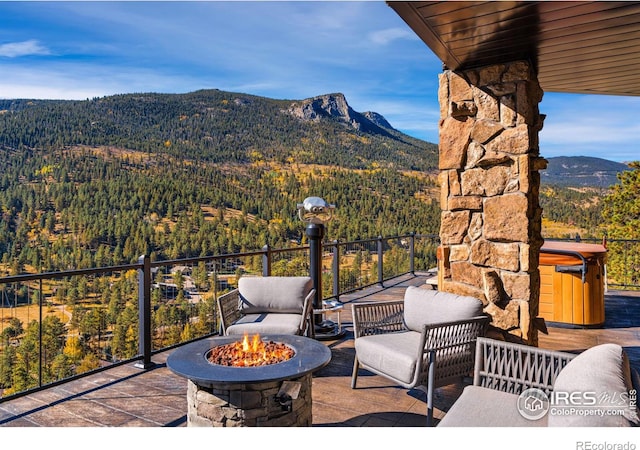 view of patio / terrace featuring a mountain view, a fire pit, and a view of trees