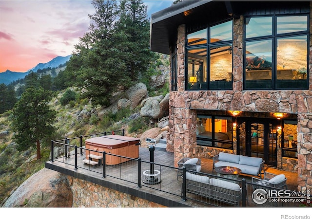 exterior space with an outdoor living space with a fireplace, a mountain view, and a hot tub