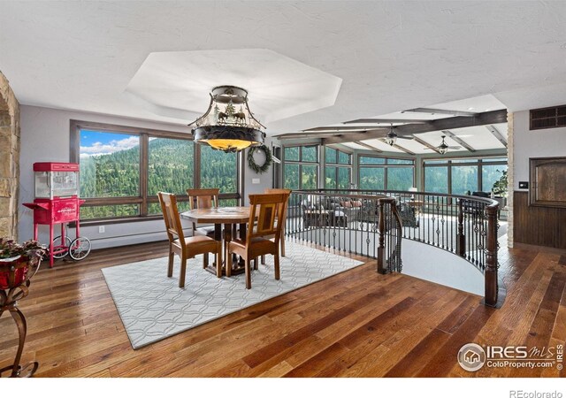 dining room with a sunroom, wood finished floors, visible vents, and a ceiling fan